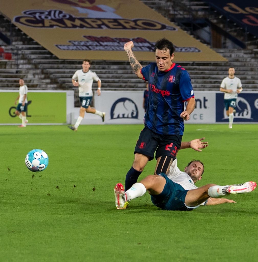 Richmond Kickers forward evades a tackle from a Sarasota Paradise defender.