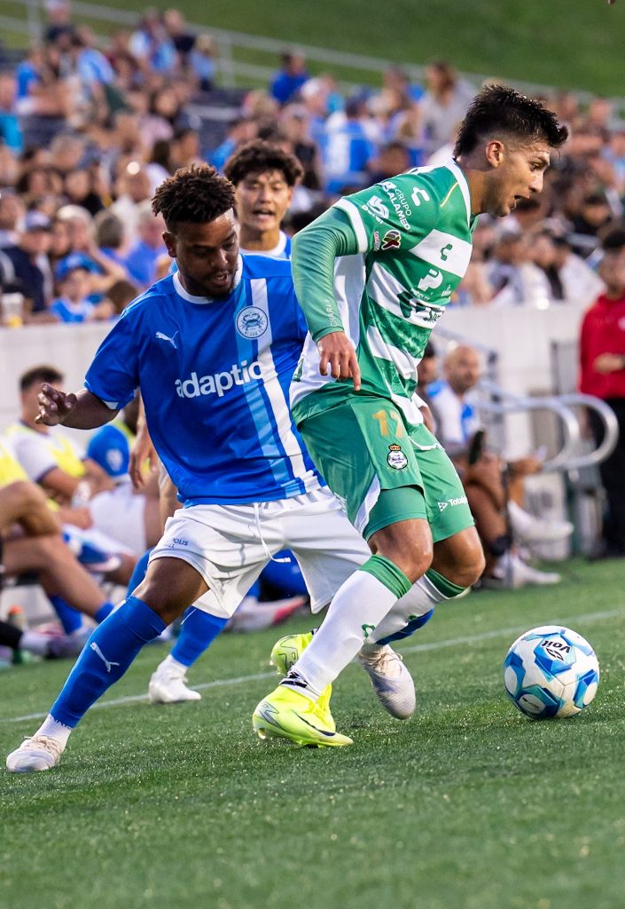 Santos Laguna defender holds off an Annapolis Blues forward while keeping possession under pressure.